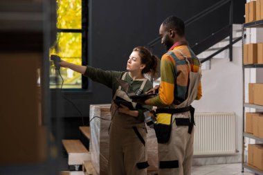 Tulum giyen çeşitli işçiler karton kutulardaki barkodları tarıyor, küçük bir işyeri e-dükkanının envanterini yönetiyor ve sevkiyat hizmetini sağlıyorlar. Çevrimiçi lojistik için paket hazırlığı yapılıyor.