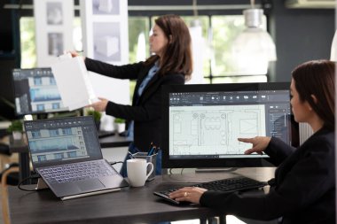 Bilgisayar ve 3 boyutlu modellerle çalışan çeşitli kadın profesyoneller yeni müteahhitler için tasarımlar hazırlıyorlar. Dokunmatik ekranda Asyalı yaratıcı tasarım mimari kat planları.