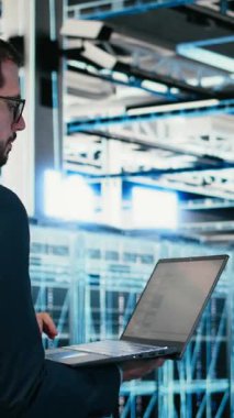 Dikey Veri Merkezi yazılım geliştiricisi dizüstü bilgisayar programı kullanılarak kaynak optimizasyonu için kod yazıyor. Sunucu merkezinde yürüyen işçiler, IT 'yi yükseltmek için dizüstü bilgisayardaki programlama betiğini kullanıyorlar