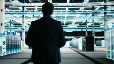 Veri merkezi teknisyeni internet hizmetlerine yardım eden mavi kablo ağ teçhizatını yönetiyor. Dijital depolama sistemleri için yapılmış sunucu çiftliğinin dijital ikiz taramasında yürüyen adam, kamera A