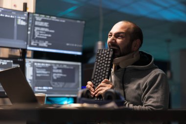 Tedirgin programcı, sürekli tekrarlanan teknik aksaklıklar yüzünden hayal kırıklığı içinde yüzünü klavyeye dayıyor. Yorgun kodlayıcı geç saatlere kadar görevde kalıyor, ekipman çalışmadığı için kızgın ve stresli..