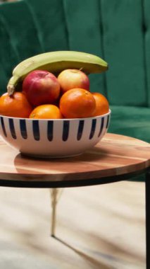 Dikey video boş modern ev tasarımı. Kanepe, koltuk ve ahşap sehpası olan şık bir oturma odası tasarımı yok. Bir kase meyve masayı süsler, sıcaklık ve sıcaklık katar.