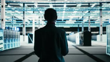 Yazılım geliştiricisi hata ayıklamak için tablet ve AR teknolojisini kullanarak veri merkezinde yürüyor. Sunucu çiftliği bilişim uzmanı mavi kablo ağ ekipmanlı süper bilgisayarlar ve kamera A 'da sistem kontrolü yapıyor.