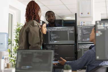 Birden fazla monitördeki kodları analiz eden çok ırklı bireyler, müşteriler için ön yüz arayüzünü geliştirmeyi planlıyorlar. Web geliştirme projesi üzerinde çalışan profesyonel geliştirici takımı.