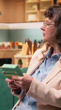 Dikey video sunucusu kadın, ilaç kutusu, günlük sağlık hizmeti, yaşlılık, yeni ilaç tedavisi için etiket bilgilerini okuyan kişi. Hastalıkların önlenmesi ve tavsiyeleri destekleme, emeklilik