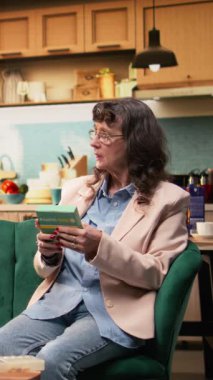 Dikey Videolu Kadın reçeteli ilaç kutusunu kontrol ediyor. Kan basıncı monitörünü hazırlayan adam. Kanepede günlük sağlık sigortası olan yaşlı çift. Evde sağlık hizmetleri, hastalık yönetimi ve rutin destek