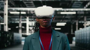 VR kulaklık teknolojisi kullanan mutlu veri merkezi teknisyeni, gelecek güvenlikli ağdan memnun. Sunucu merkezi güvenliğini sanal gerçeklik simülasyonuyla arttırdıktan sonra memnun olan neşeli işçi, kamera A