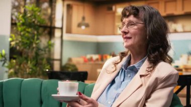 Emekli kadın bir fincan kahveyle rahatlıyor ve yalnız vakit geçiriyor, kanepede oturuyor ve evdeki huzurlu anları hayal ediyor. Yaşlılıkta sağlık ve sükunet.