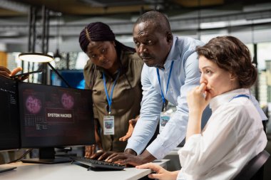 Programmer in startup office requesting help from coworkers to fix hacking attempt warning. IT employee and colleagues brainstorming how to fix cybercrime data breach affecting systems