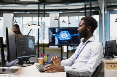 Yazılım geliştiricisi kod yazıyor, makine öğrenme API 'leri geliştiriyor. Ofiste çalışan Afrikalı Amerikalı bir adam, yapay zeka teknolojisi kullanarak yazılımsal hatalar yapıyor.