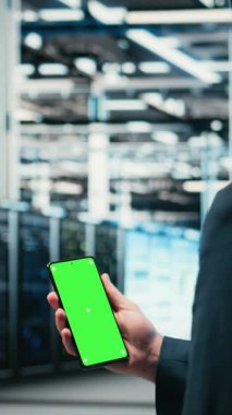 Veritabanı yöneticisi tarafından kullanılan dikey video yeşil ekran akıllı telefon kablo ağ dişlilerinin internet hizmetlerine yardımcı olması. İşçi, sunucu çiftliğinde dijital depolama için cep telefonu kullanıyor