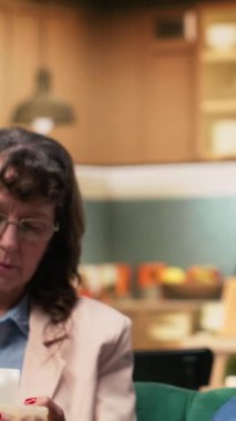 Dikey videolu yaşlı kadın günlük haplarını alıyor ve erkek tansiyon monitörünü hazırlıyor, çift evde günlük sağlık hizmeti veriyor. Refahı destekleyen kişisel bakım ve