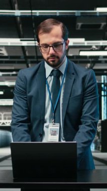 Yükseltilmiş sunucu rafları kurmak için laptop ve artırılmış gerçeklik kullanan dikey video veri merkezi teknisyeni. Sunucu çiftlik performansını, VFX kaplamasını ve kamerayı izlemek için otomasyon araçları kullanan işçiler