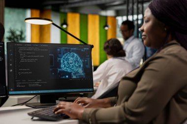 Yapay zeka şirketinin iş yerindeki sistem yöneticisi kod incelemeleri için PC 'yi kullanıyor. Makine öğrenme algoritmaları tasarlamak ve uygulamak için ofis masasındaki bilgisayar programını kullanan bilişim uzmanı