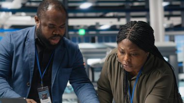 Siyahi mühendislik uzmanları ve yöneticileri bir güneş enerjisi üretim tesisindeki operasyonel iş akışlarını inceliyorlar. Yenilenebilir enerji üretimi ve gelişimi için takım çalışması entegre ediliyor. Kamera B.