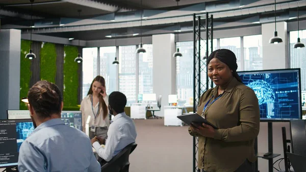 Ofisteki mutlu kadın mühendis yapay zeka senaryoları kullanarak tekrarlanan görevler yapıyor. Jolly Afro-Amerikan Geliştirici Yapay Zeka kullanarak uzun metrajlı uygulamayı hızlandırıyor, kamera A