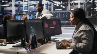 Veri merkezindeki paniklemiş sistem yöneticisi PC ekranındaki casus yazılım uyarısına tepki veriyor, acil müdahale protokolü başlatılıyor. İşçi hacklenen ekipman sistemlerini tamir etmeye çalışıyor, kamera A