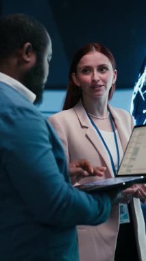 Dikey video mühendisleri dizüstü bilgisayar kullanarak yapay zeka nöral ağ evriminin ilerlemesini izler. AI makine öğrenme teknolojisinin hızlı gelişimini izleyen takım arkadaşları