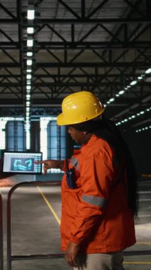 Mühendislerden oluşan dikey video ekibi, robot yazılımı, laptop araçları, ağır endüstri atölyesi, kaynak istasyonlarıyla çevrili. Robot kol bileşeniyle montaj hattı otomasyonu sağlanıyor, makine salonu.