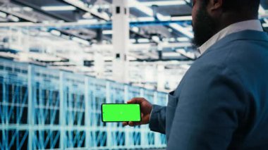 Elektroniği optimize etmek için sunucu çiftlik işçisi tarafından kullanılan yeşil ekran akıllı telefonu. Sistem performansını izlemek ve darboğazları düzeltmek için krom anahtar telefon kullanan veri merkezi yöneticisi, kamera A