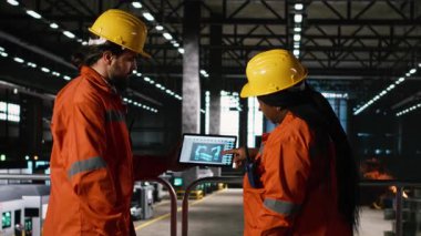 Çeşitli personel, endüstriyel depodaki dizüstü bilgisayar yazılımında otonom robot kol sistemini denetliyor. Mühendisler endüstri salonundaki büyük ölçekli üretim süreci için yüksek teknolojili robotları sağlıyorlar..