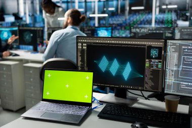 Veri merkezinde mühendisler tarafından yapay zeka ile geliştirilmiş sunucu sistemleri kurarken kullanılan yeşil ekran modelleme dizüstü bilgisayarı. Sunucu merkezindeki krom anahtar defter. İşçiler yapay zeka kullanarak donanım geliştiriyor.