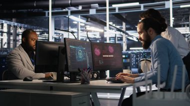 Veri merkezindeki kaygılı teknisyenler fidye yazılımının neden olduğu kilitlenmeye tepki veriyorlar. Güvenlik ihlallerini değerlendiren ve hasarı kontrol altına almak için çabalayan bilişim uzmanları, kamera A