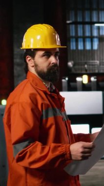 Dikey Video Mühendisi tesis boyunca yürüyor üretim planlarını, teknik planlarını, ağır sanayi deposunu inceliyor. Üretim salonu makine talimatları, düzen çizimleri içerir.