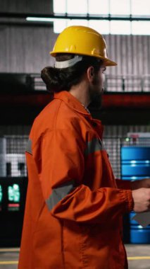 Dikey Video Adam mühendisi, planlar, çizimler ve yerleşim planları, makine dairesi üzerinde çalışıyor. Metal işçiliği, ağır ekipman ve üretime rehberlik eden ileri teknoloji ile dolu sanayi bölgesi