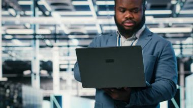 Bilgisayar kullanarak sunucu çiftliğinde yazılım geliştirici, ağ yönetimi viralizasyonu yapıyor. Veri Merkezi 'ndeki Afrikalı Amerikalı adam bilgisayarları kontrol ediyor. Not defteri, kamera B