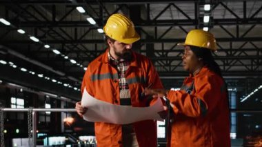 İki farklı mühendis, ağır sanayi fabrikasının planlarını ve inşaat talimatlarını analiz ediyor. Endüstriyel üretimi sağlamak için ağır donanım operasyonları için teknik planlar kullanılıyor.