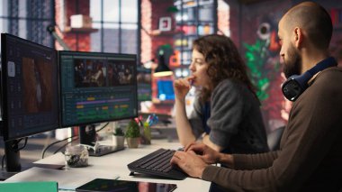 Yapay zeka sohbet robotu ve montaj yapıcı yazılımla çalışan video düzenleme ekibi, arka plan videosu düzenleme ve çift monitörlerde klipleri karıştırma. Yaratıcılık sürecinde olan profesyonel erkek ve kadın. Kamera A.