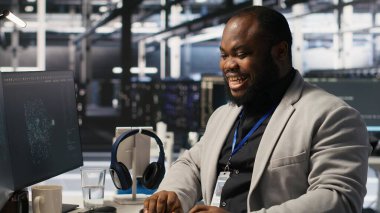 Süper bilgisayar sistemi bakımını bitirdikten sonra neşe içinde dans eden neşeli bir veri merkezi çalışanı. Başarılı yapay zeka model eğitim sonuçlarından çok memnun olan mutlu mühendis sunucu ekipmanlarını denetliyor, kamera A