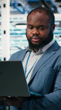 Gülümseyen sunucu merkezi çalışanının dikey video portresi platformların performansını ve güç tüketimini izliyor. Veri merkezindeki mutlu adam ekipmanı denetliyor, endüstri standartlarına ve kameraya uyum sağlıyor.