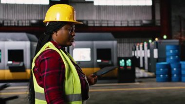 Üretim salonu boyunca endüstriyel işletim istasyonlarını denetleyen kadın mühendis. Depo tesisinde ağır endüstriyel metal işleri yapan bir tablet. Kaynak kaynaklarından kıvılcımlar çıkan mühendislik fabrikası.