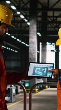 Vertical Video Diverse personeli, endüstriyel depodaki dizüstü bilgisayar yazılımında otonom robot kol sistemini denetlemektedir. Mühendisler sanayideki büyük ölçekli üretim süreci için yüksek teknolojili robotları sağlıyorlar.