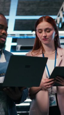 Operasyonel etkinliği arttırmak için tablet ve laptop kullanan dikey video sunucu odası takım arkadaşları. Mühendislik ekibi veri merkezinde beyin fırtınası yapıyor, dişli takozlarını izlemek için aygıtlar kullanıyor