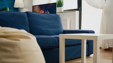 Boş modern oturma odası, duvarda rahat bir kanepesi olmayan, arka planda ve televizyonda çalışma yeri olan zarif bir tarzı olan. İçerisi mavi duvarlı, güzel dekore edilmiş dairesi olan kimseyle dolu değil.