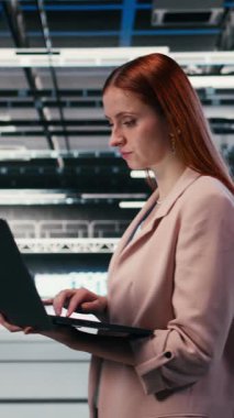 Elektroniği optimize eden dikey video, sunucu çiftliğindeki dizüstü bilgisayar ve kadın geliştirmeler yapıyor. Veri merkezinde yürüyen sistem performansı, not defteri ve kadın teknisyen, darboğazları tanımlıyor