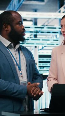 BT çözümlerini dizüstü bilgisayarla hesaplayan bir girişimi yönetmek için işbirliği yapan dikey video veri merkezi çalışanları. Gelecekteki sunucu çiftliği çalışma alanını tartışan, izleyen programcılar.