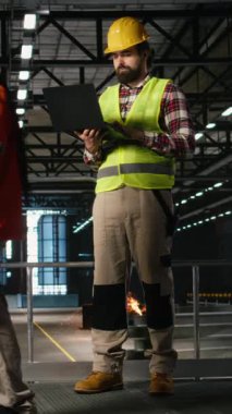 Dikey Video Endüstriyel Mühendisliği, metalik kirişler, mekanik sistemler ve ağır ekipmanlarla çevrili, üretim salonundaki ağır makineleri izliyor. Mühendislik ve imalat süreci