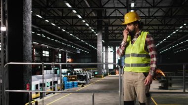 Ağır endüstri tesislerinde telsiz kullanan profesyonel mühendis portatif radyo vericisiyle üretim hattını koordine ediyor. İki yönlü iletişimi olan makine dairesi.
