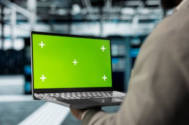 Sunucu performans sorunlarını kontrol etmek için yüksek teknoloji veri merkezinde yeşil ekran laptop kullanan teknisyenleri kapatın. Sunucu merkezi işyeri çalışanı, taklit defter kullanarak donanımı yavaşlatan hataları düzeltiyor