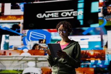 Tablet kullanan bir kadın, anında kişisel video tavsiyeleri alıyor. Afrika kökenli Amerikalı kullanıcı, dijital çağın tadını çıkararak sınırsız yayın olanakları sağlıyor