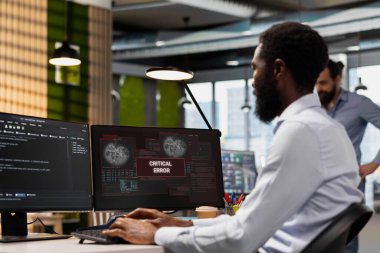 Teknoloji başlangıç ofisinde kritik hata alarmını çözen mühendis, sorun çözme sistemi uyarıları. IT uzmanı kritik hata iletisini ele alıyor, ofis ekipmanlarını hata ayıklıyor