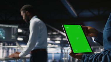 AI LLM görselleştirmesini gözden geçiren meslektaşın yanında izole ekran tableti kullanarak sunucu merkezini kapat. Veri merkezi çalışanı makine öğrenme sistemlerini izlemek için model aygıtı kullanıyor,