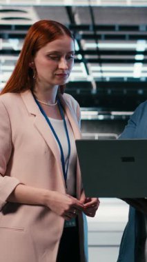 Dikey video sunucusu çiftlik yöneticisi indüksiyon sırasında interne dizüstü bilgisayar kullanmayı ve elektroniği optimize etmeyi öğretiyor. Veri merkezi takım lideri ve stajyer sistem performansını izlemek için not defteri kullanıyor, kamera B