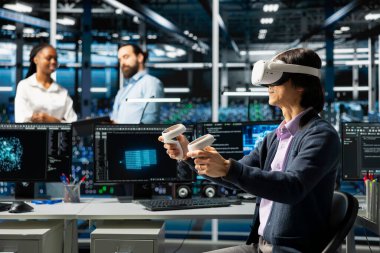VR kulaklık kullanan veri merkezi programcısı, yapay zeka uygulamalarını destekleyen veritabanları üzerinde çalışıyor. Sanal gerçekliği kullanan sunucu odası çalışanı algoritmaları geliştirmek için yapay zeka