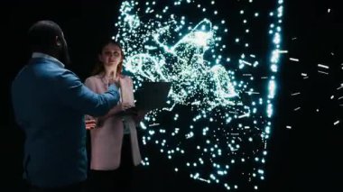 Programcılar nöral ağ nöronları haritasını dizüstü bilgisayar ve artırılmış gerçeklik teknolojisiyle optimize ediyorlar. Takım çalışanı iş arkadaşları AI modeli sinaptik ağırlıkları not defteri, kamera A ile ayarlıyorlar.