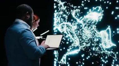 Yapay zeka başlangıç veri bilimadamları dizüstü bilgisayarla derin öğrenme algoritmaları uyguluyorlar, işbirliği yapıyorlar. İş arkadaşları yapay zeka sinir ağı mimarisini cihaz, kamera B ile kodluyor, değiştiriyor